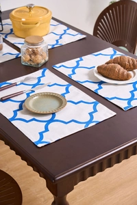 Close-up of blue geometric floral placemats on a rustic wooden dining table with kitchenware