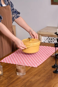 Yellow enamel cast iron pot with stainless steel knob on a wooden table in home kitchen