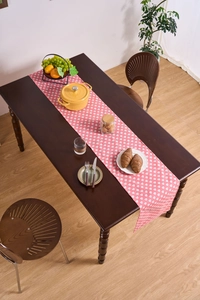Close-up of pink table runner with white heart prints on a dark wooden dining table
