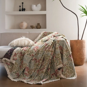 Pink floral jacquard sofa throw blanket with decorative tassels in a cozy home setting