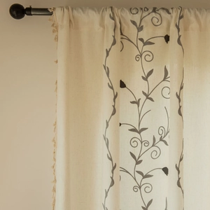 Close-up of beige cotton linen curtain with plant embroidery and delicate side tassels