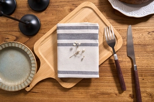 Close-up of gray and white striped linen napkin placed on a rustic wooden dining tray