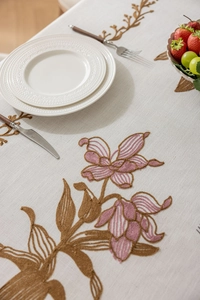 Gros plan détaillé sur la texture brodée florale d'une nappe en lin crème