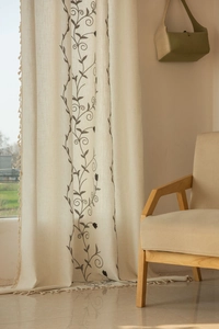 Detail of beige cotton linen curtain with vine embroidery and tassel fringe edges