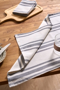 Detailed macro view of gray and white striped linen napkin fabric on a wooden table surface