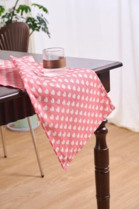 Detail view of pink table runner with white heart patterns on dark wood furniture