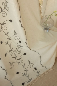 Detail of beige linen fabric featuring green tulip embroidery and decorative tassels