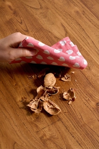Close-up of pink heart-patterned cloth cleaning walnut shells on a wood table