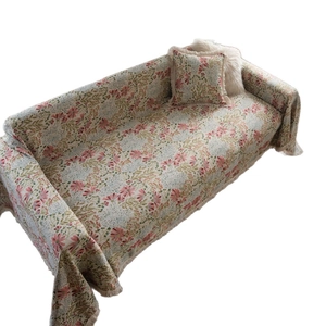 Pastel floral sofa cover with pink blossoms and green leaves featuring fringed edges