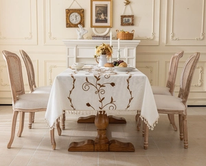 Detail of vintage cream tablecloth with dark brown floral embroidery and elegant tassels