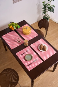 Primer plano de manteles de tela rosa con corazones blancos sobre mesa de madera