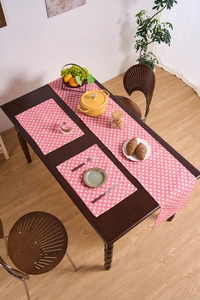 Close-up of pink table runner set with white heart patterns on dark wood dining table