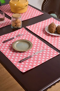 Detailed view of pink table runner with white heart prints on rustic wooden dining surface