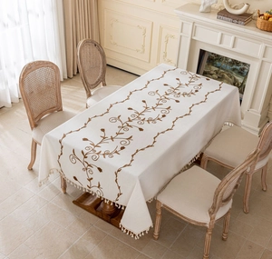Detail of cream rectangle tablecloth with vine floral embroidery and tassel fringe edges