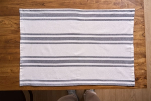 Close-up of grey and white striped linen napkin texture on a dark wooden table surface