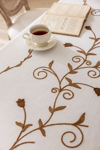 Macro detail of vintage floral embroidery and fringe on the cotton linen tablecloth