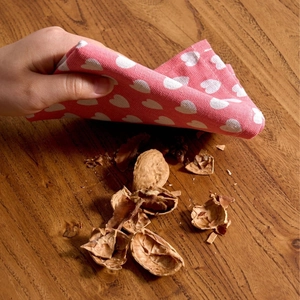 Pink cloth napkin with white heart patterns on a dark wood table with nuts