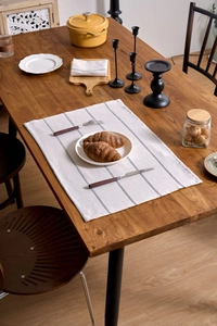 Close-up of black striped linen table mat on a wooden table with dining props