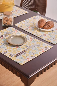 Detalle del mantel individual de tela floral con costuras precisas en mesa de madera