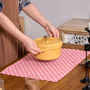 Vibrant yellow enamel cast iron Dutch oven on a pink heart pattern placemat decor