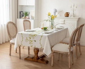 Detail of embroidered vine pattern and elegant beige tassels on linen tablecloth