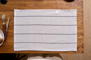 Detail of black striped cotton linen table mat on a dark wood background table