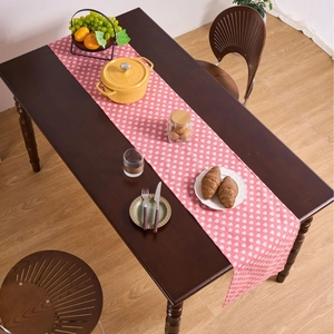 Pink table runner with white heart patterns on dark wood table for home dining decor