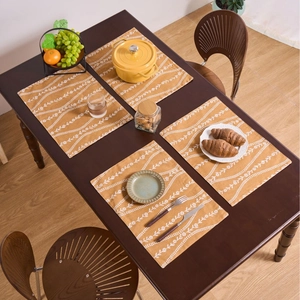 Set di quattro tovagliette gialle con motivi floreali su tavolo da pranzo in legno