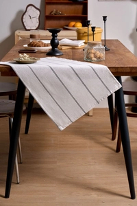 Close-up of cream cotton linen table runner with black stripes on a dark wood table