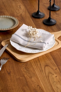 Close-up of linen napkin with stripes on a ceramic heart plate and wooden tray