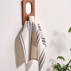 Nordic grey and white striped linen napkin hanging on a wooden rack with a white candle
