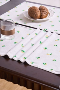 Primer plano de mantel individual de tela con flores y cítricos sobre mesa de madera