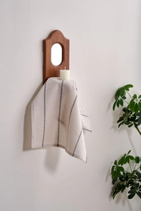 Detail of striped linen napkin hanging on a wooden rack in a cozy home setting