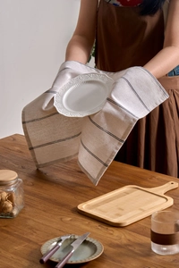Close-up of beige linen napkin with black stripes and white lace embossed ceramic plate
