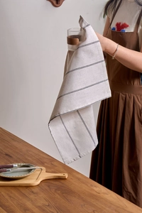 Detail of black and white striped linen napkin wiping a glass in a kitchen setting