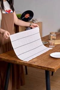 Detail of minimalist white and black striped cotton tea towel on a wooden table