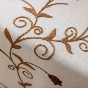 Floral embroidered tablecloth with brown vine patterns and rustic linen texture