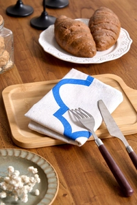 Detail of blue geometric print fabric napkin on wood tray with home dining decor
