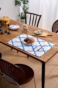Detail of blue Moroccan trellis pattern cloth napkin and placemat set on wood table