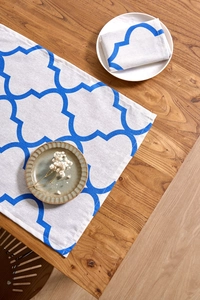 Close-up of blue geometric clover pattern on cream linen table runner and matching napkin