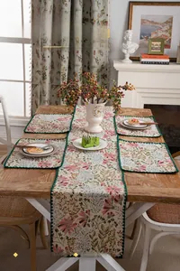 Detail view of floral table runner with green shell stitch embroidery on vintage wood