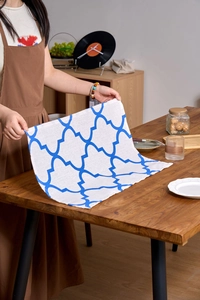 Blue geometric tile print fabric napkin on a wooden dining table with home decor