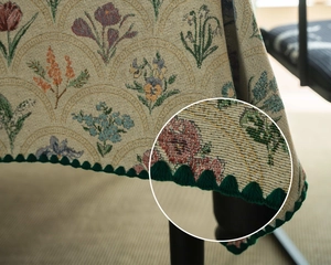 Macro detail of French retro jacquard tablecloth with floral patterns and green pompom edge