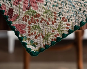 Close-up of floral jacquard fabric with elegant pink lily embroidery and scalloped green edges