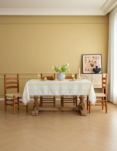 Detailed view of beige tablecloth with yellow geometric patterns and white fringe tassels