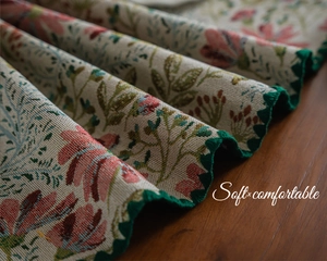 Macro shot of jacquard table runner featuring pink lily embroidery and scalloped green edges