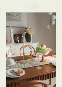 Detail of floral embroidery on pink table runner with vintage brass candle holder