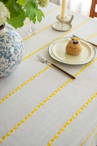 Close-up of yellow leaf embroidery and cotton linen texture on cream tablecloth