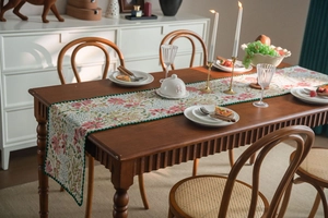 Detail of floral table runner with pink lilies, embroidery and green scalloped edges