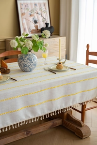 Detail of cream tassel fringe and yellow embroidered texture on cotton linen tablecloth